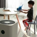 Child sitting at table next to an air purifier