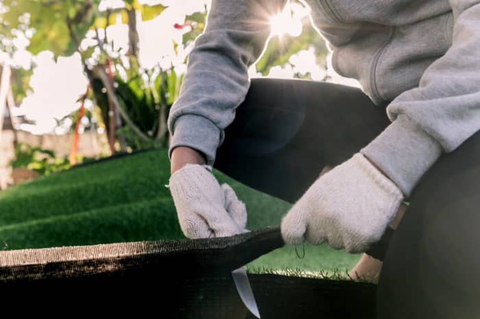 A worker cuts artificial grass with a knife during installation