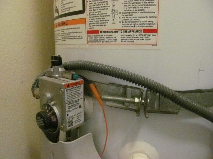 improperly installed water heater strap behind gas valve