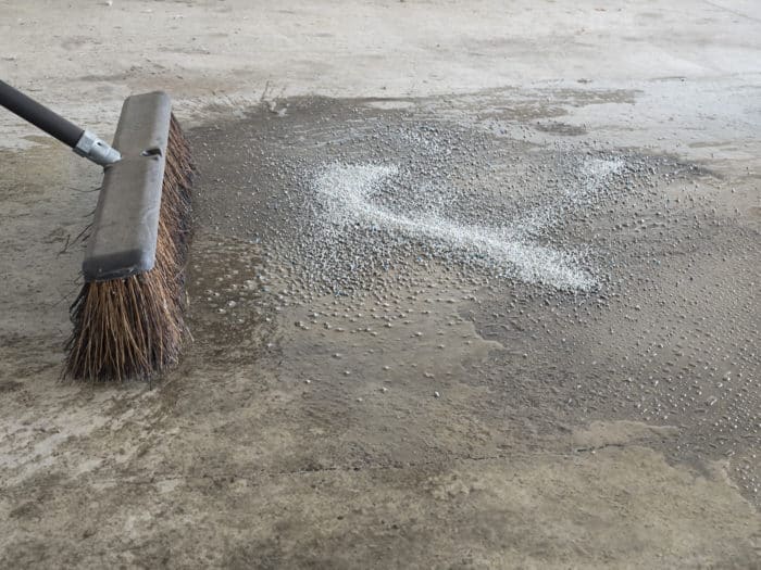 Cat litter absorbing oil spill before preparing garage concrete for epoxy