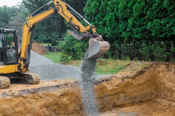 excavator dumping gravel for home foundation