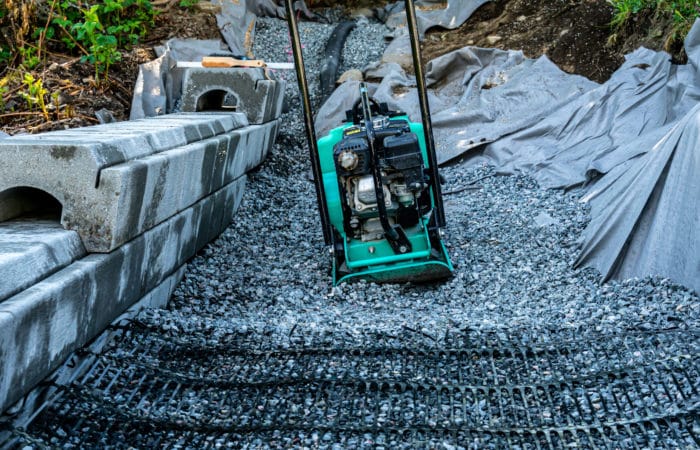 Geotextile plastic on rock with compactor