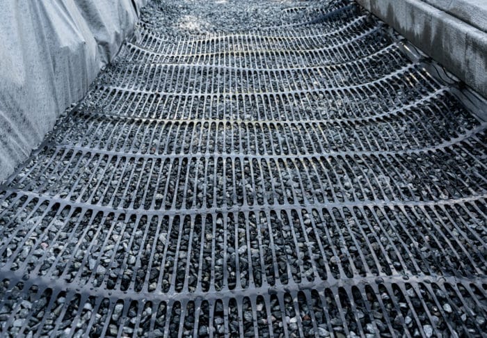 geotextile mat over crushed rock behind retaining wall stabilizing soil