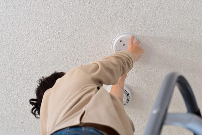 A person Installing smoke alarm on the ceiling