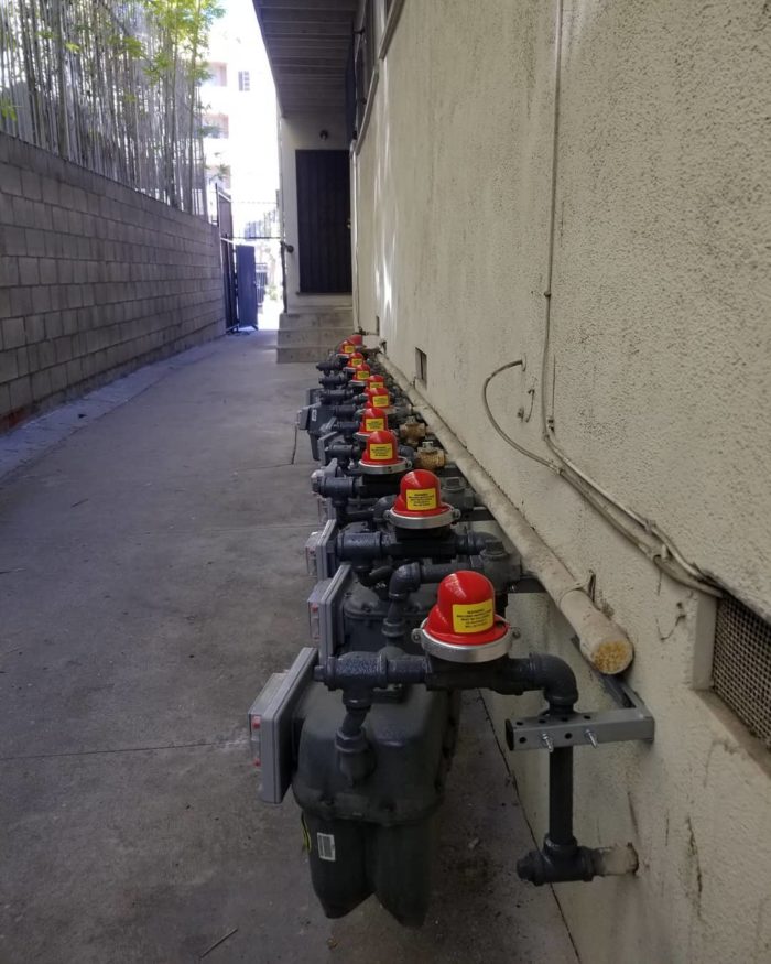 Line of natural gas meters with red seismic shut off valves installed