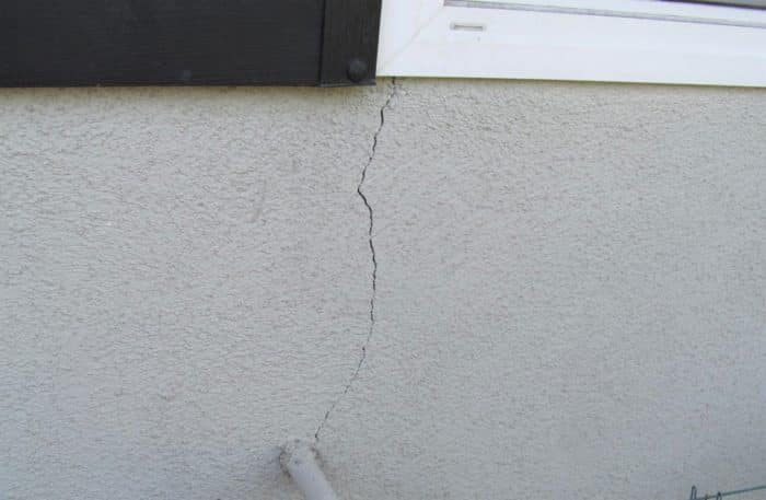 window corner crack to pipe in stucco wall